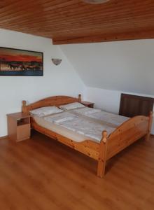 a wooden bed in a room with a wooden floor at Aleksa apartman in Lesencetomaj