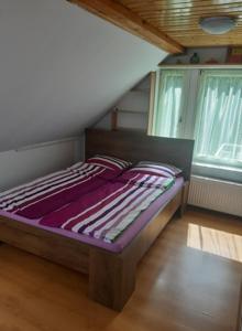 a bed sitting in a room with two windows at Aleksa apartman in Lesencetomaj