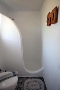 a white bathroom with a toilet and a rug at Christou Homes in Steni Vala Alonissos