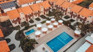 an overhead view of a swimming pool with tables and umbrellas at Pousada do Timoneiro in Arraial do Cabo