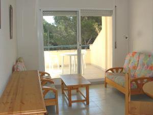 a living room with a table and chairs and a sliding glass door at Magda Park D 1D in L'Escala