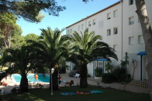 a building with palm trees in front of a swimming pool at Magda Park D 1D in L'Escala