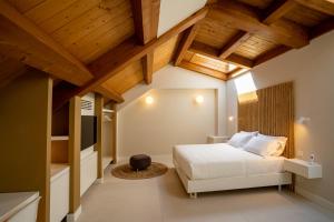 a bedroom with a white bed and wooden ceilings at Villa Corallo Relais Chateaux in SantʼOmero +83 photos