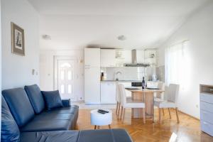 a living room with a blue couch and a kitchen at Apartment Pelicaric Sali Dugi otok in Sali