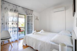 a white bedroom with a bed and a balcony at Apartment Pelicaric Sali Dugi otok in Sali