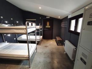 a room with three bunk beds and a hallway at Casa Carmina Hostel in Muros de Nalón