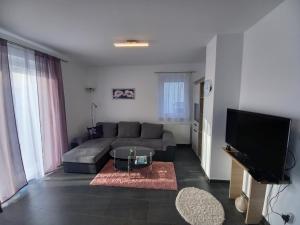 salon z kanapą i telewizorem z płaskim ekranem w obiekcie Laura Luxury Apartman Gyenesdiás w Gyenesdiás