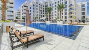 a pool with chairs and an umbrella next to a building at TOWN SQUAR PARK VIEW in Dubai