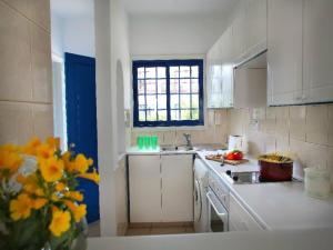 a kitchen with white cabinets and a vase of yellow flowers at Villa Julie in Protaras