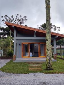una pequeña casa con un árbol en primer plano en Chalé dos Pássaros en Gramado