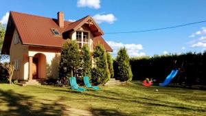 una casa con cortile attrezzato per il parco giochi di fronte ad essa di Bociani Domek a Płaska
