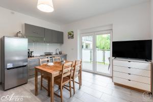 a kitchen with a wooden table and a refrigerator at Apartamenty Ambra in Dębina