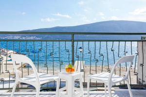 a table and chairs on a balcony overlooking the water at Rosic Apartments Baosici in Bao&scaron;ići
