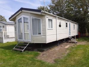 a white tiny house sitting in a yard at Country Coastal Holidays - Families and Couples only in New Romney
