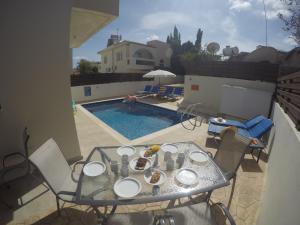 a table with plates on it next to a swimming pool at Paradiso Villa in Protaras