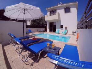 a swimming pool with blue chairs and an umbrella at Paradiso Villa in Protaras