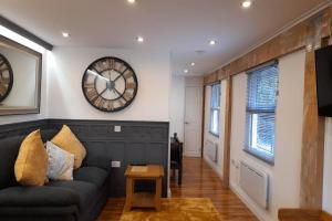 ein Wohnzimmer mit einem Sofa und einer Uhr an der Wand in der Unterkunft THE CLOCKHOUSE, ROuGHTON in Roughton