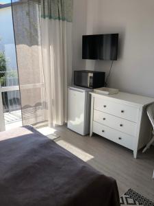 a bedroom with a bed and a dresser with a television at Ostrowianka in Ostrowo