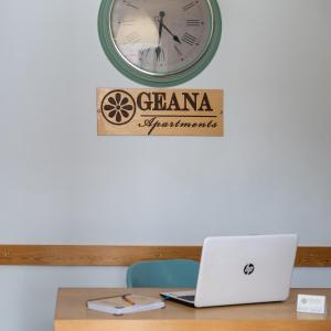 a desk with a laptop and a clock on a wall at Geana Apartments in Chania