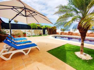 a pair of chairs and an umbrella next to a swimming pool at Villas Anais in Callao Salvaje