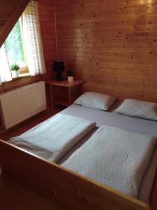 two beds in a wooden room with two windows at Logarska koča in Fokovci