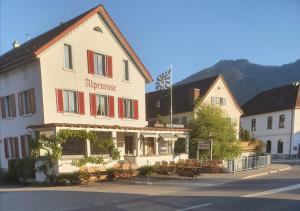 a building with tables and chairs in front of a street at Hotel Alpenrose in Maienfeld