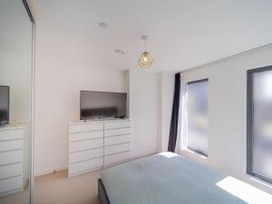 1 dormitorio con 1 cama, TV y ventana en Pass the Keys Modern Balcony Apartment in the heart of Stratford en Londres