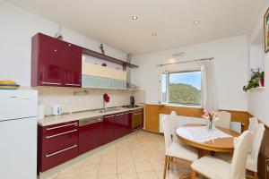 a kitchen with red cabinets and a table and a table and chairs at Agriculture & Holiday house Lasko in Goveđari