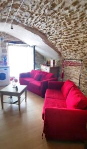 a living room with red couches and a stone wall at Chambre d hote de charme avec plein d authenticité du 13 ème siècle in Châteauneuf-du-Pape