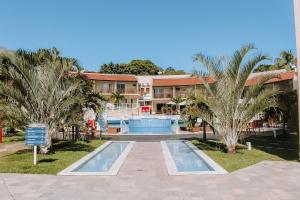 a resort with a swimming pool and palm trees at Qavi - Triplex com Jacuzzi no centro de Pipa #SolarÁgua181 in Pium