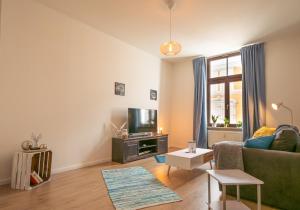 ein Wohnzimmer mit einem Sofa und einem TV in der Unterkunft Blue Chili 18 Zentrales CITY-Apartment am Hasselbachplatz, 4 Personen in Magdeburg