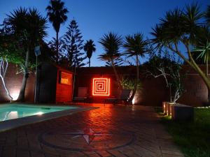 a house with a neon sign next to a swimming pool at Samadhi Home in Chiclana de la Frontera
