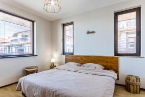 a bedroom with a large bed and two windows at Anistalia - Villa Acacia in Lozenets