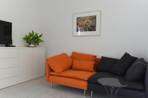 pomarańczowa kanapa w salonie z telewizorem w obiekcie Buric House - Apartments Klasik and Studio Mini w Rovinj