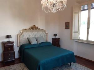 ein Schlafzimmer mit einem blauen Bett und einem Kronleuchter in der Unterkunft Villa Magnolia Park in Pisa
