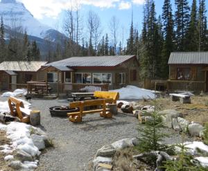 uma cabana de madeira com uma mesa de piquenique e neve em HI Rampart Creek - Hostel em Saskatchewan River Crossing