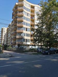 duży budynek apartamentowy z samochodami zaparkowanymi przed nim w obiekcie Apartment Vesta w Kobuleti