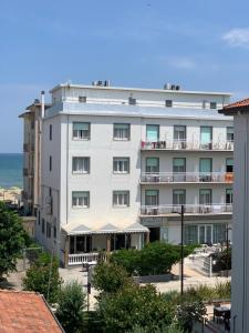 a white building with the ocean in the background at Hotel Laika in Rimini