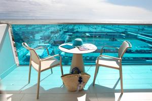 balcón con mesa, 2 sillas y piscina en Hotel Pineta, en Sottomarina