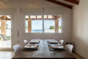 a dining room with a wooden table and a large window at Terracotta beach house in Lefkímmi