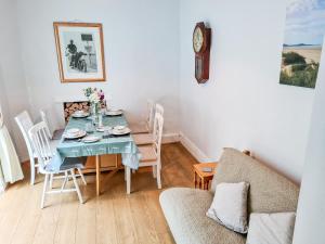 a dining room with a table and chairs and a clock at 62 Danlan Road in Burry Port