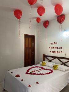 a bed with red balloons and a cake on it at Pousada do Holandês in Canoa Quebrada