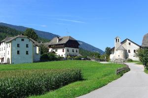 a group of buildings in a field next to a road at Pension Hofer in Brunico