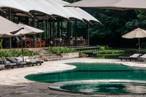 a swimming pool with chairs and umbrellas and a restaurant at Rodavento Valle de Bravo in Valle de Bravo