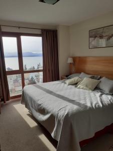 um quarto com uma cama grande e uma janela grande em Maqui Departamentos em San Carlos de Bariloche