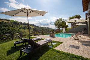 Benevello的住宿－Cascina Pajanòt，一个带两把椅子和一把遮阳伞的庭院和一个游泳池