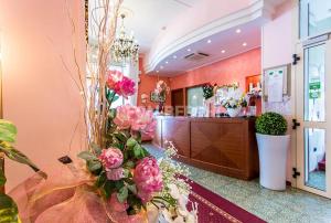 a lobby with pink flowers and a cash register at Hotel Bisanzio in Cesenatico