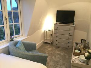 a bedroom with a dresser with a tv and a chair at Glebe House in Deal