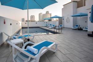 una piscina con sedie e ombrelloni su un tetto di City Avenue Al Reqqa Hotel a Dubai