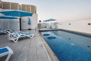 - une piscine avec des chaises et des parasols à côté d'un bâtiment dans l'établissement City Avenue Al Reqqa Hotel, à Dubaï